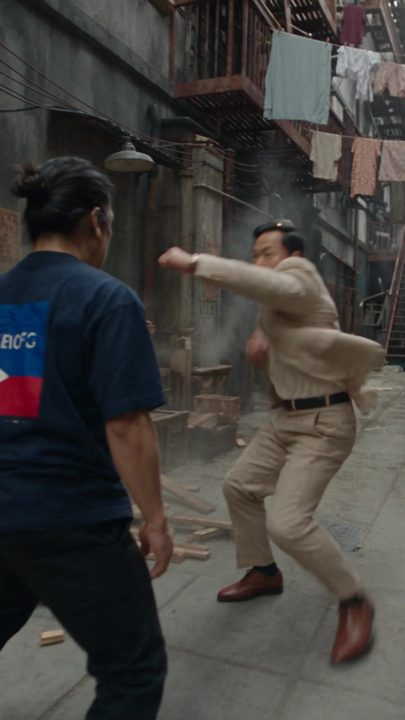 Video frame: a garbled flag print appears on the back of RA's shirt